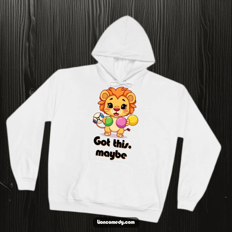 Funny cozy hoodie with a determined kawaii lion juggling three colorful balls, perfect for gifting.